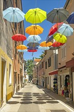 Street with souvenir shops and colourful umbrellas in the historic town centre of Novigrad