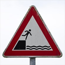 Sign warns people not to fall off the edge into the water