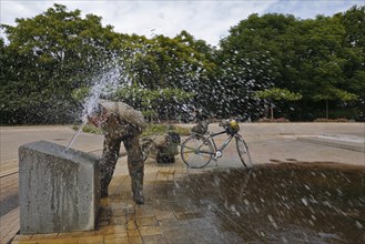 Cycle tourist refreshes himself at a public water feature