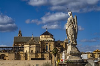 Statue of the Archangel Raphael on the Roman Bridge and the Mezquita in Cordoba