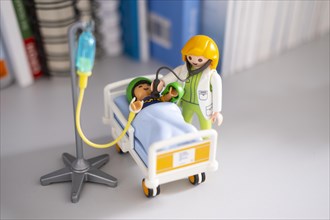 A Playmobil doctor examines a patient with a stethoscope