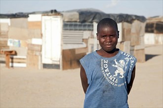 Teenager posing in front of improvised shacks