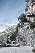 Photo with reduced dynamic range saturation HDR of view of steep rock face next to mountain road in French Maritime Alps