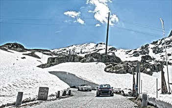 Photo with reduced dynamics saturation HDR of two Porsche 911 driving on mountain pass alpine mountain road alpine pass road pass old Gotthard road with cobblestones to Gotthard pass at St Gotthard