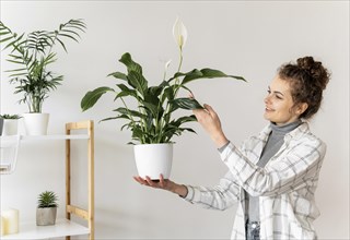 Medium shot woman holding plant