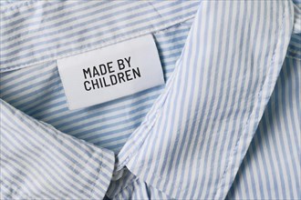 Clothing label with text saying 'Made by children'. Child labor concept