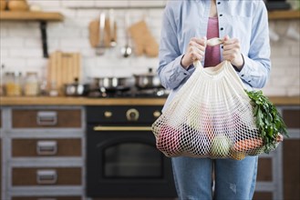 Adult woman holding reusable bag with organic vegetables