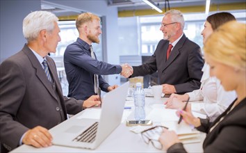 Businesspeople looking two businessmen shaking hands business meeting