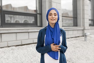 Medium shot gorgeous girl with hijab smiling outside
