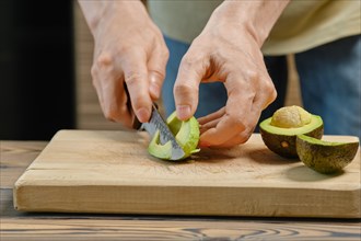 Unrecognizable man cuts avocado on slices