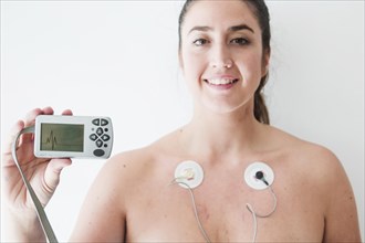 Lady with electrodes holding monitor with cardiogram
