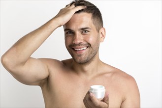 Portrait happy man applying hair wax standing against white background