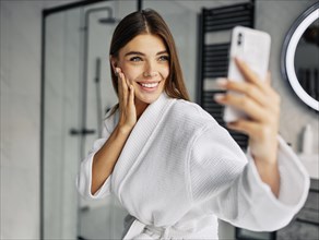 Positive young woman bathrobe taking selfie