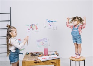 Little girl painting posing girl chair