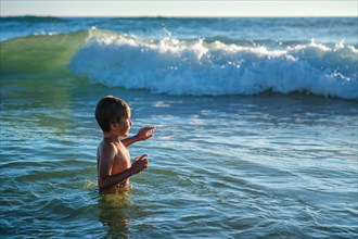 Boy has fun enjoys jumps dives in ocean sea waves of Atlantic Ocean. Fonta da Telha beach