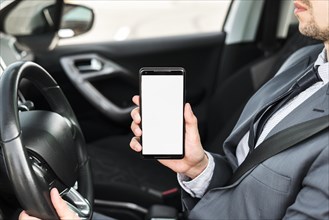 Close up businessman driving car showing mobile phone with white display screen