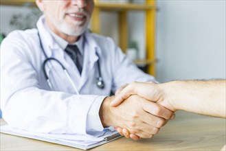 Smiling doctor shaking hand patient