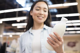 Cheerful asian female holding bottle milk supermarket