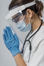 Side view female doctor with medical mask face shield praying