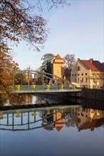 Autumnal coloured trees with iron bridge over the river Maltsch with the city wall of the historical old town of Ceske Budejovice