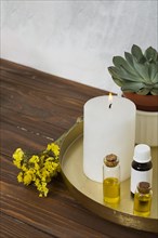 (Limonium) flower with white large lighted candle essential oil bottle wooden desk