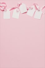 White tags pink ribbon top background with space text