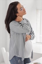 Side view pregnant woman holding her neck