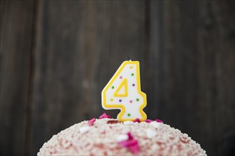 Number 4 candle birthday cake against blue wooden background