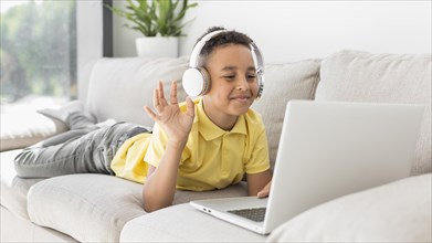 Student with headphones waving laptop