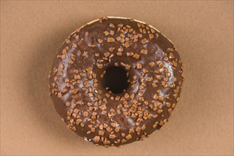 Dark chocolate doughnut with sprinkles brown background