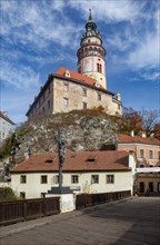 Pedestrian bridge over the Vltava with wayside cross and Krumlov Castle with castle tower