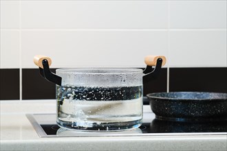 Water boiling in glass saucepan on electric stove