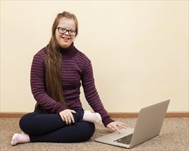 Front view smiley girl with down syndrome laptop