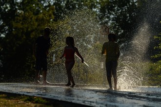 Children playing water in scorching weather in a park. Kehl