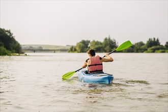 Man kayaking lake with paddle