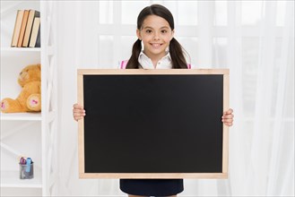Smiling child school uniform showing blackboard classroom