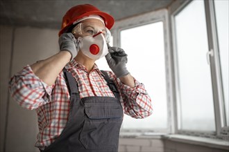 Female construction worker with helmet headphones wearing face mask