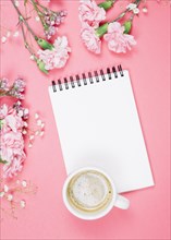 Overhead view coffee cup blank notepad with carnations gypsophila