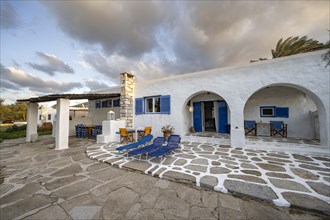 White Cycladic house with terrace with chairs and sun loungers