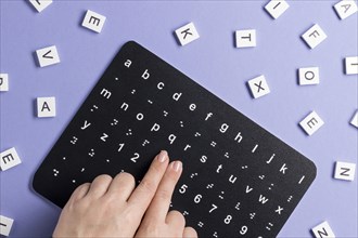 Fingers touching braille alphabet board