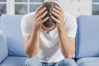 Frustrated man suffering from headache sitting sofa