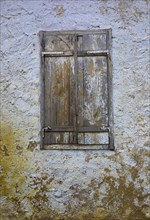 Weathered house facade with an old closed window