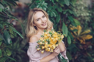 Portrait blonde young woman holding yellow flower bouquet
