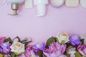 High angle view moisturizing cream fake flowers pink background
