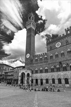 Atmospheric clouds at Piazza del Campo with its bell tower Torre del Mangia and the town hall Palazzo Pubblico