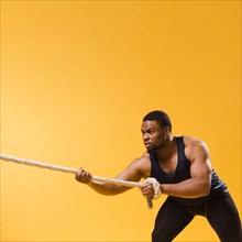 Athletic man gym outfit pulling rope with copy space
