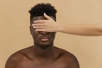 Close up white hand covering black man eyes