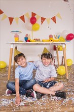 Happy male friends playing with confetti during birthday celebration