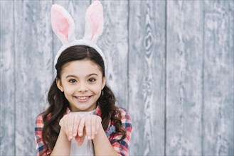 Close up girl posing like bunny against wooden gray background