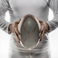 Front view male rugby player holding ball with both hands